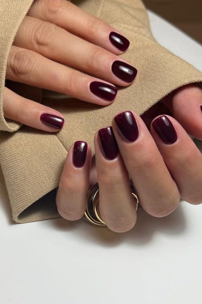 Dark burgundy oval nails with a knit sweater