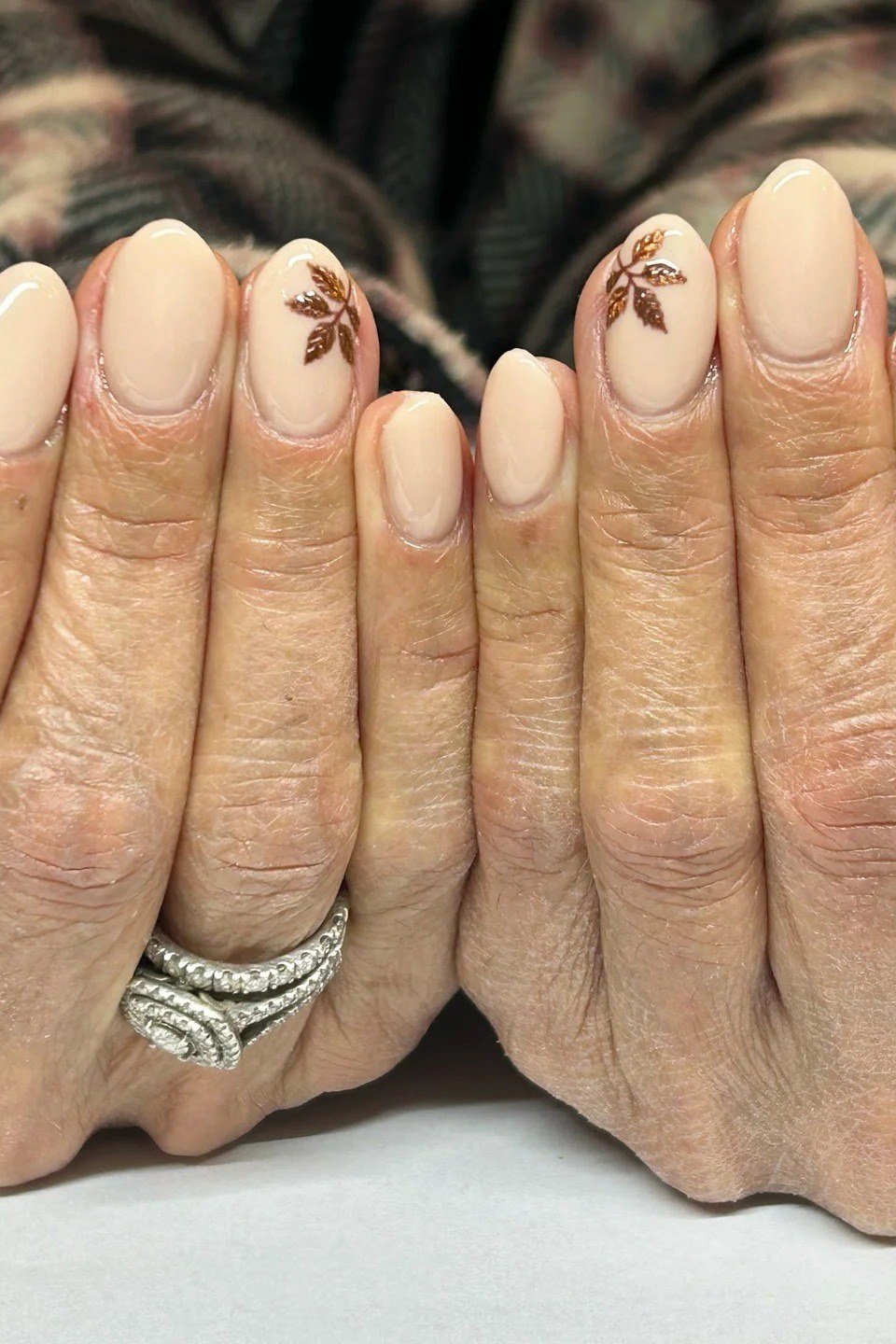 Nude nails with a leaf accent on mature hands