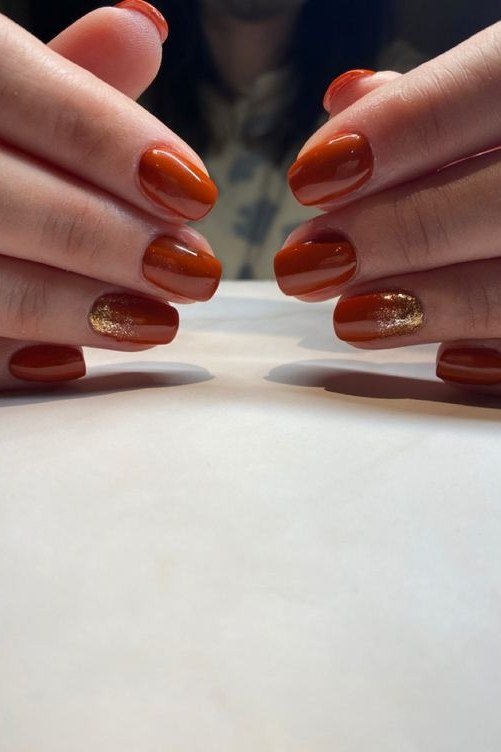 Rust orange nails with gold glitter accent for women over 60