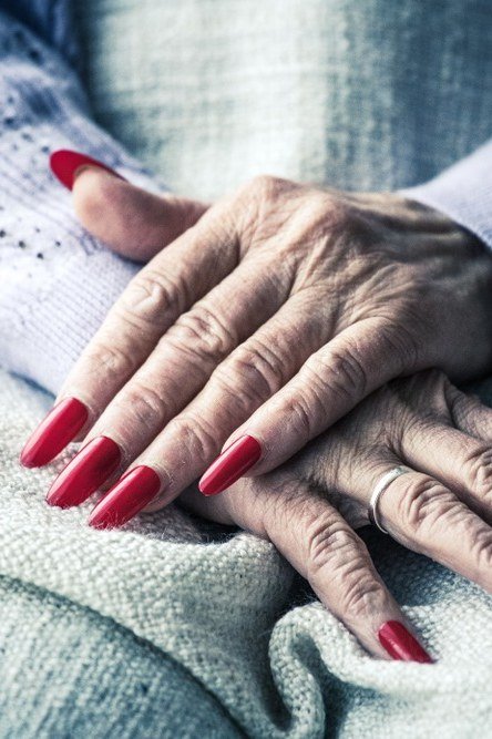 Deep red polish on long oval nails with knit sweater