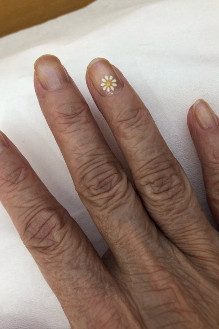 Nude nails with single tiny daisy accent nail art