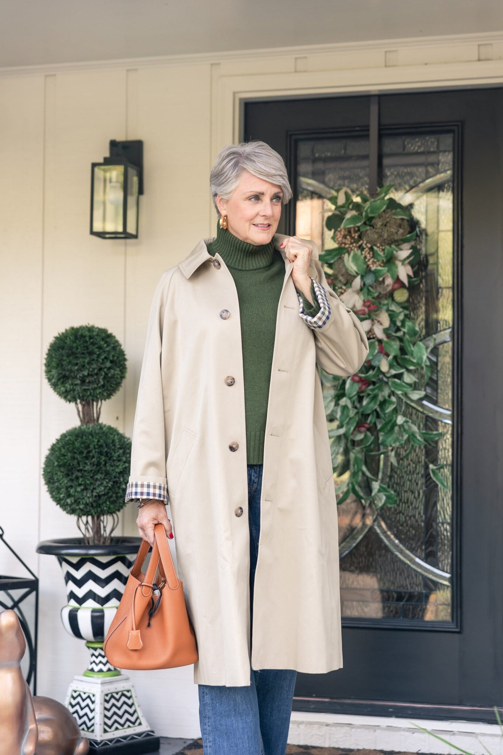 Beige trench coat with green turtleneck jeans and tan bag