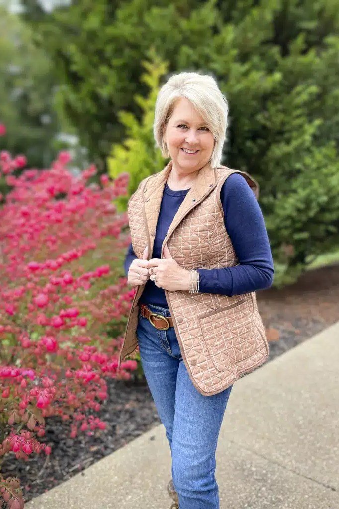 Tan quilted vest with navy sweater and jeans fall look