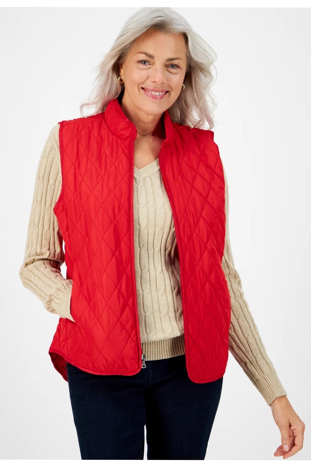 Red quilted vest with cream cable knit sweater and dark jeans