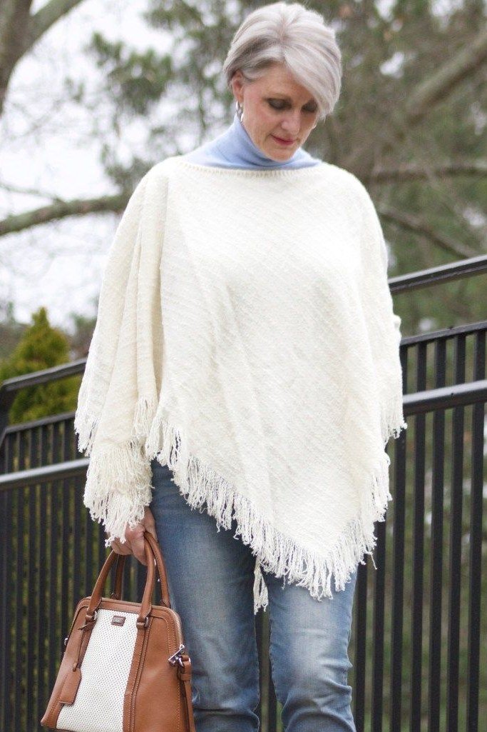 White fringe poncho with jeans and tan bag fall look