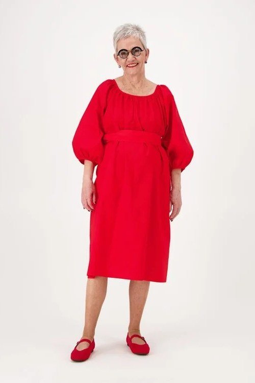 Red balloon-sleeve fit-and-flare midi dress for older women, worn by smiling woman with glasses