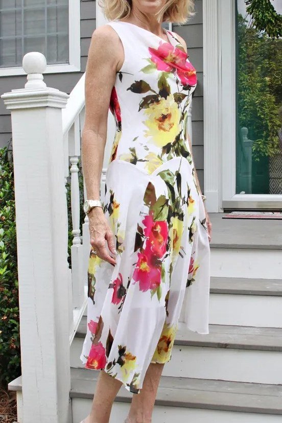 White fit-and-flare dress with pink and yellow florals for women over 60 on patio