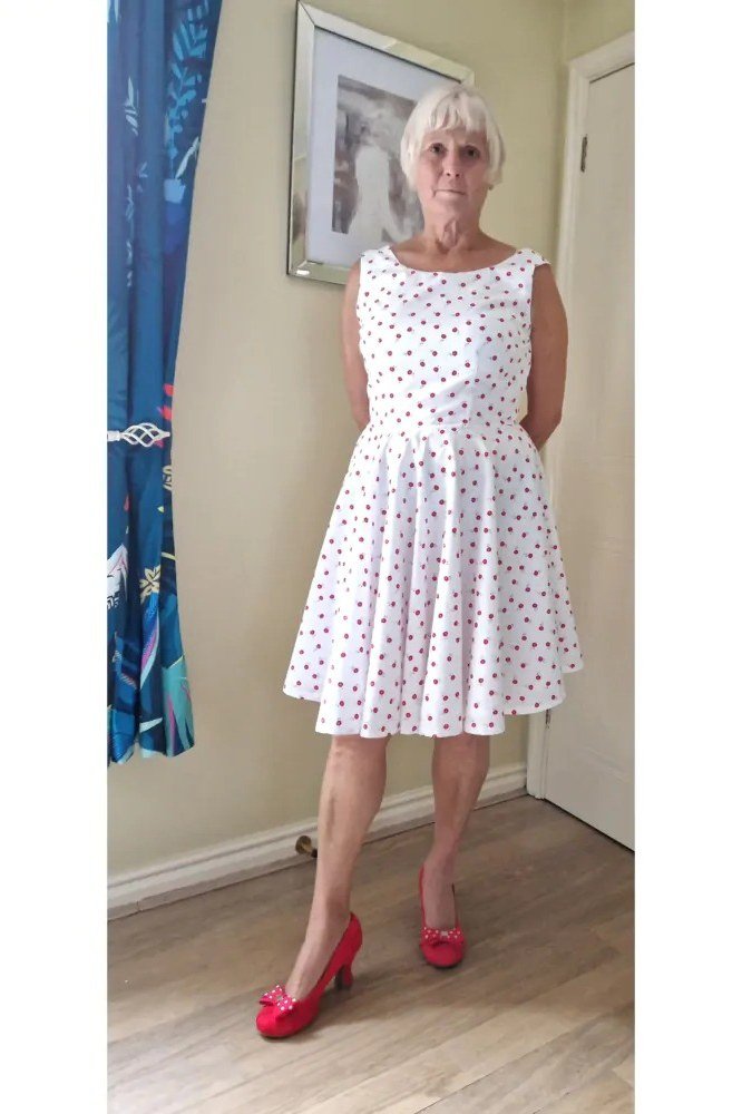 White polka-dot fit-and-flare dress with red heels for grey-haired woman