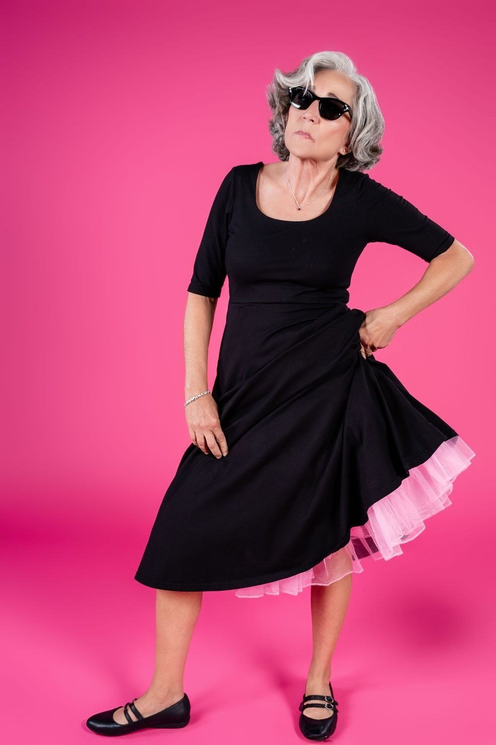 Black fit-and-flare dress with pink underskirt for older women with sunglasses