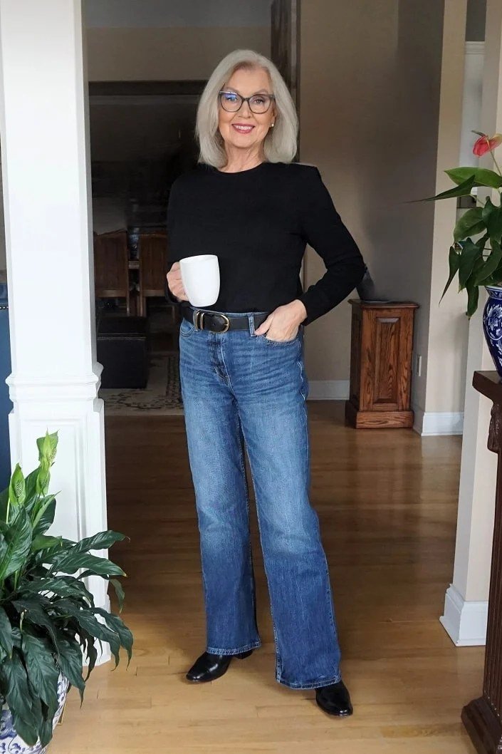 A black long-sleeve top with medium-wash wide jeans is cozy and unfussy. It is the look of fall mornings done right, warm mug in hand. Glasses and gray hair look fantastic against simple black. Comfort-first, but still intentional.