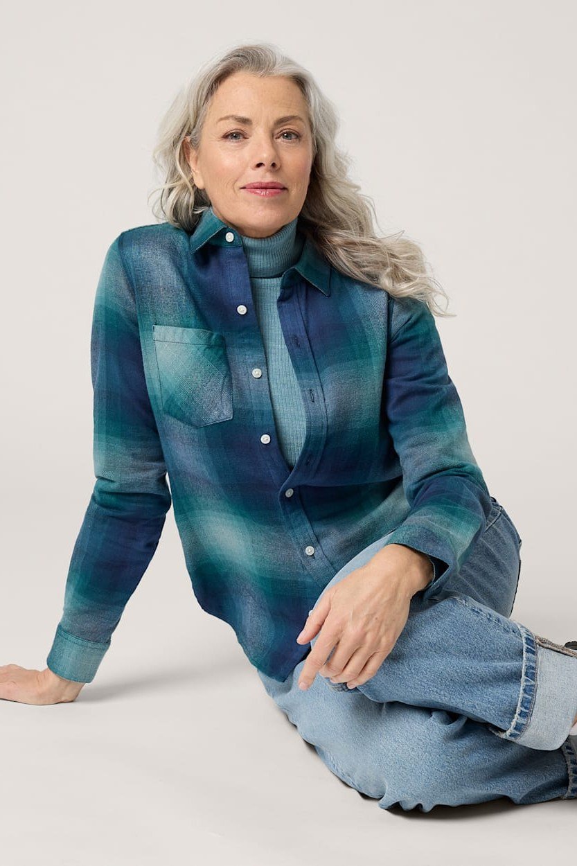 A teal plaid flannel shirt with light-wash jeans is cozy fall comfort. The rich teal glows against gray hair. The relaxed flannel fit is easy and wearable. A perfect weekend or apple-picking outfit.