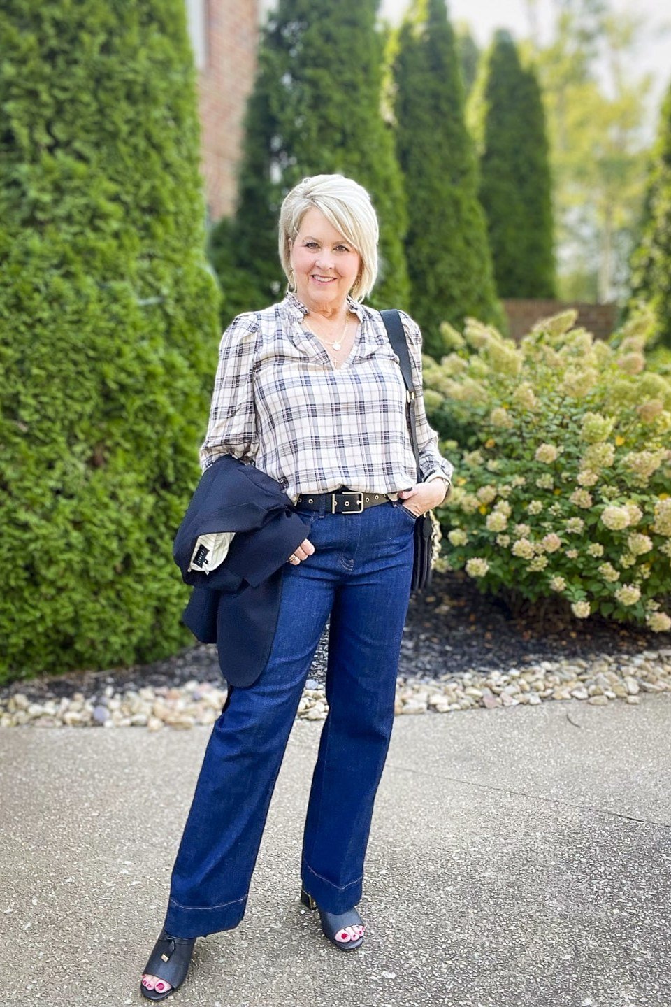 A gray-and-white plaid shirt with dark straight jeans is understated and chic. A navy jacket draped over one arm readies you for temperature swings. Black flats finish it simply. An easy travel or errand outfit.