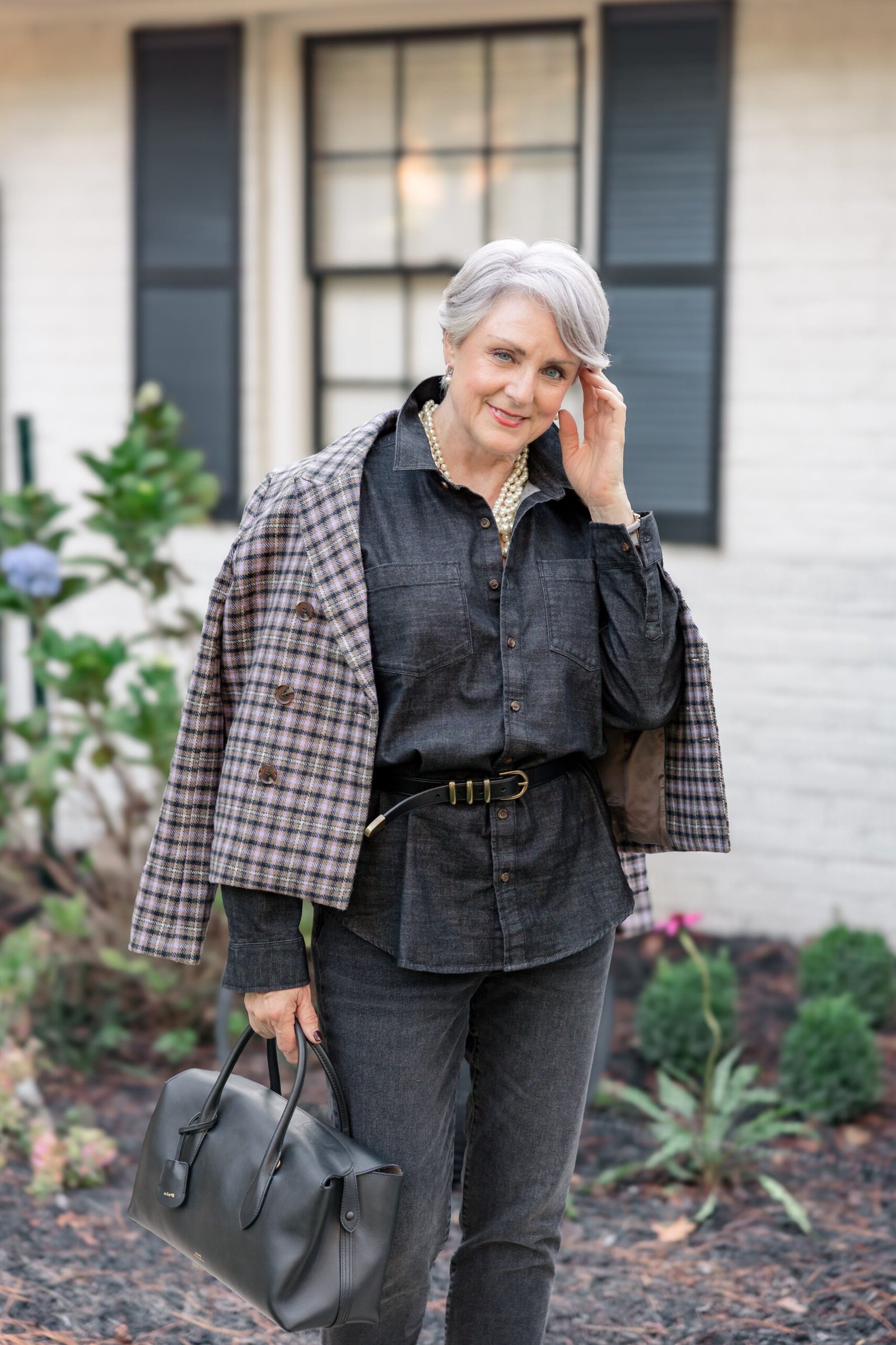 A houndstooth blazer draped over the shoulders with a black shirt and dark jeans is pure sophistication. A black handbag keeps it sleek. The classic pattern adds heritage charm. Stunning for the theater or a nice dinner.