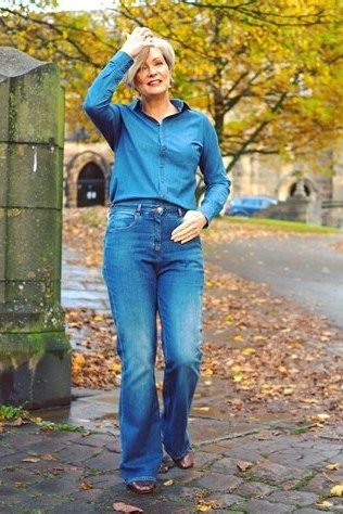 A bright blue button shirt with medium-wash flared jeans is joyful fall dressing. The blue pops against golden autumn leaves. The flared leg adds retro charm. A happy outfit for weekend outings.