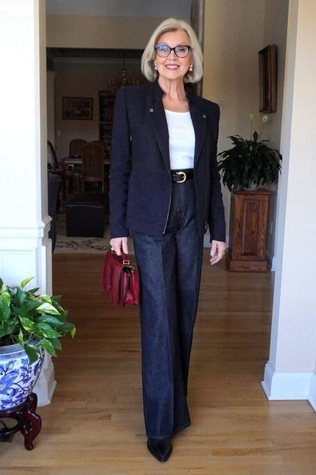A navy blazer over a white top with dark wide-leg jeans gets a pop from a red handbag. The red is a joyful surprise. Wide legs add drama and movement. A confident look for days when you want to stand out.