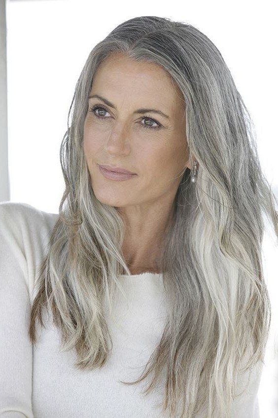 Long silver-grey waves, white top, soft smile grey hairstyle for women over 50