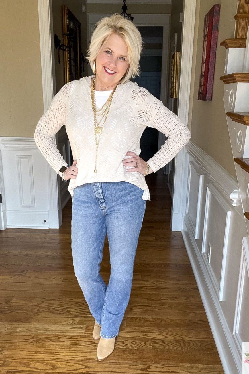 White knit sweater with blue jeans in a hallway, timeless fall look for women over 40