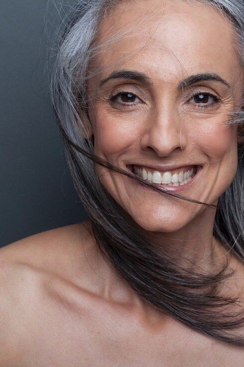 Long salt-and-pepper hair, windblown, smiling grey hairstyle for women over 50