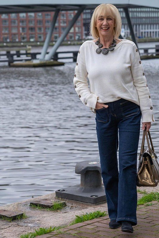 White sweater with dark skinny jeans by the waterfront, relaxed fall look for mature women