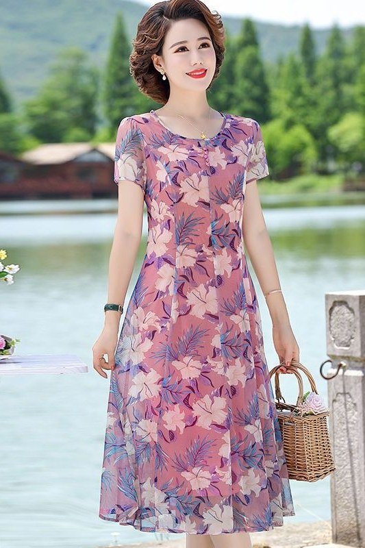 Pink floral midi dress with a wicker basket by a lake, sweet summer look for women over 60