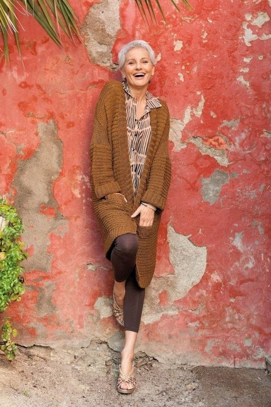 Tan cardigan with dark outfit against a red wall, stylish fall look for mature women