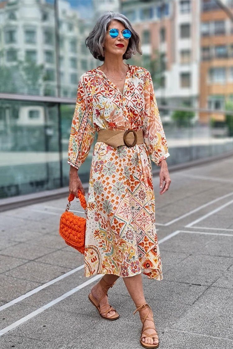 Orange floral midi dress with a big belt and orange woven bag, bold summer street style for women over 60