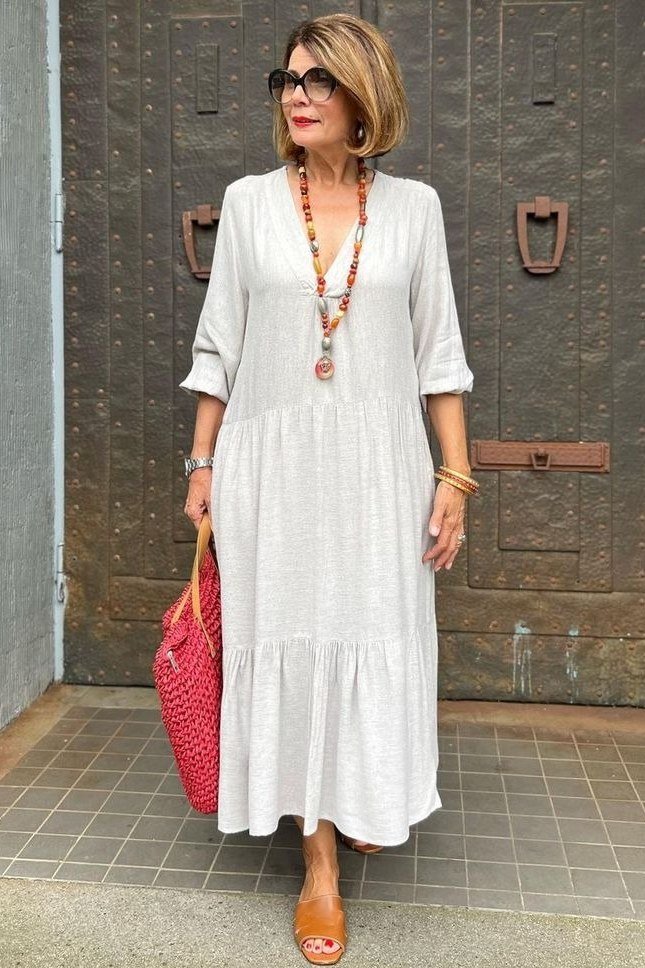 White tiered maxi dress with a red woven bag and long necklace, crisp summer look for women over 60