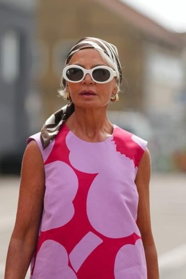 Bold pink sleeveless shift dress with a big floral print and sunglasses, confident summer style for mature women