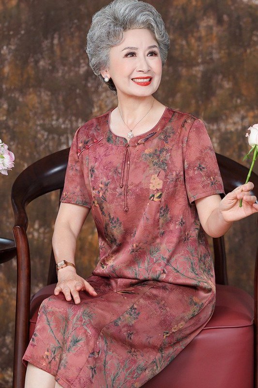 Rose print midi dress on an older woman seated with a white rose, timeless summer style