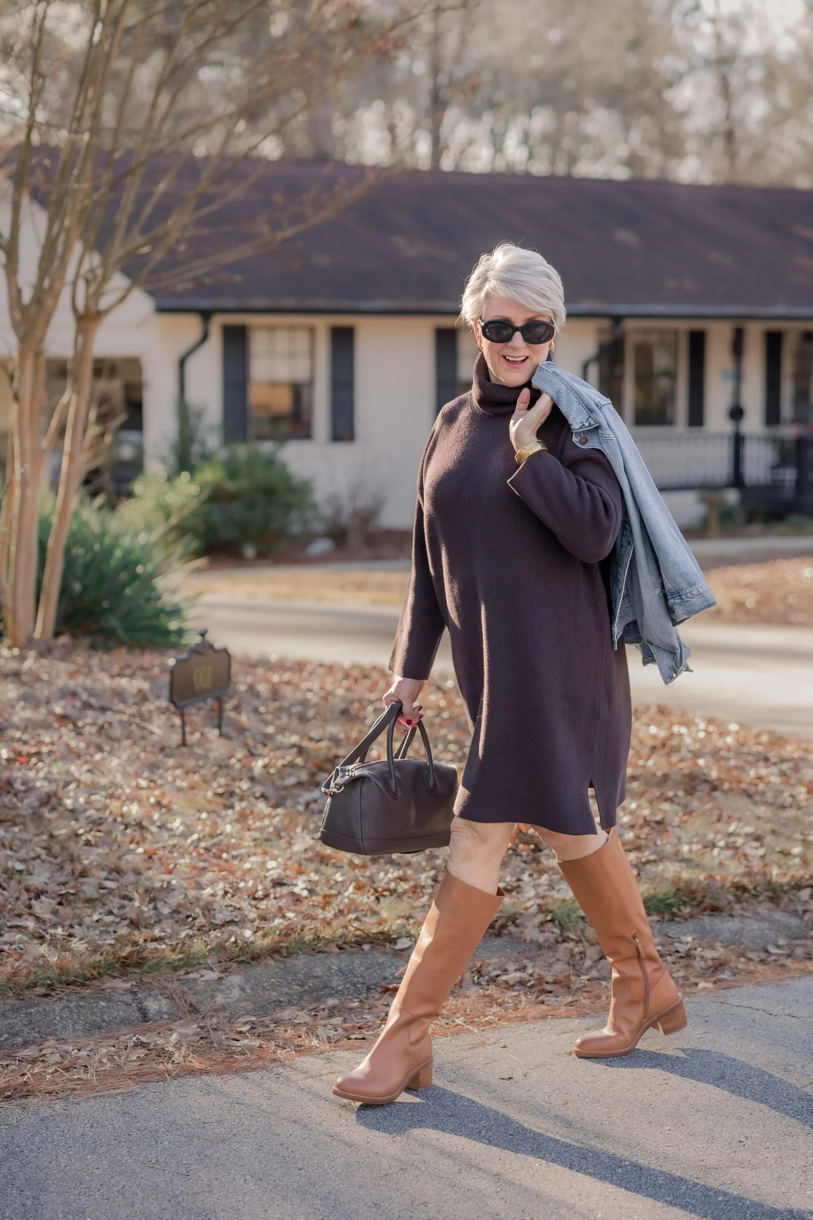 Dark grey sweater dress with tan boots outdoors, contrast boot fall outfit for older women