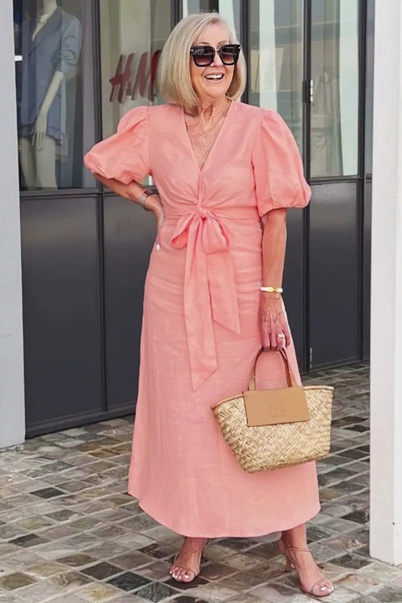Peach puff sleeve midi dress with a bow neckline and woven bag, sweet summer city style for women over 60