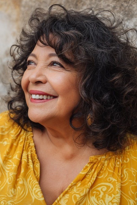 Dark curly bob on a woman over 60, front view
