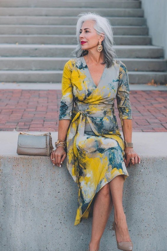 Flattering yellow and blue floral wrap dress, sitting on wall for women over 60