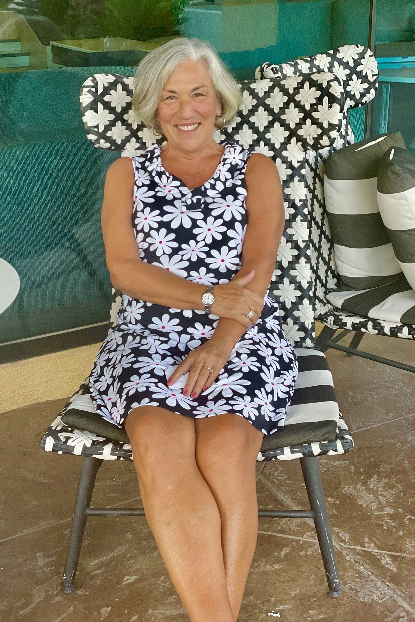 Navy and white floral sleeveless dress seated on bench