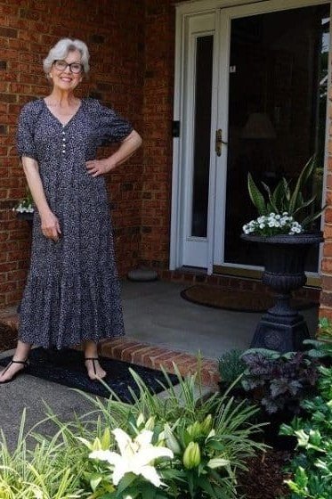 Dark small-floral maxi dress standing by brick house