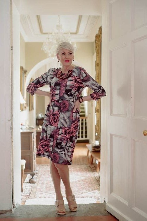 Dark floral midi dress posing at white doorway