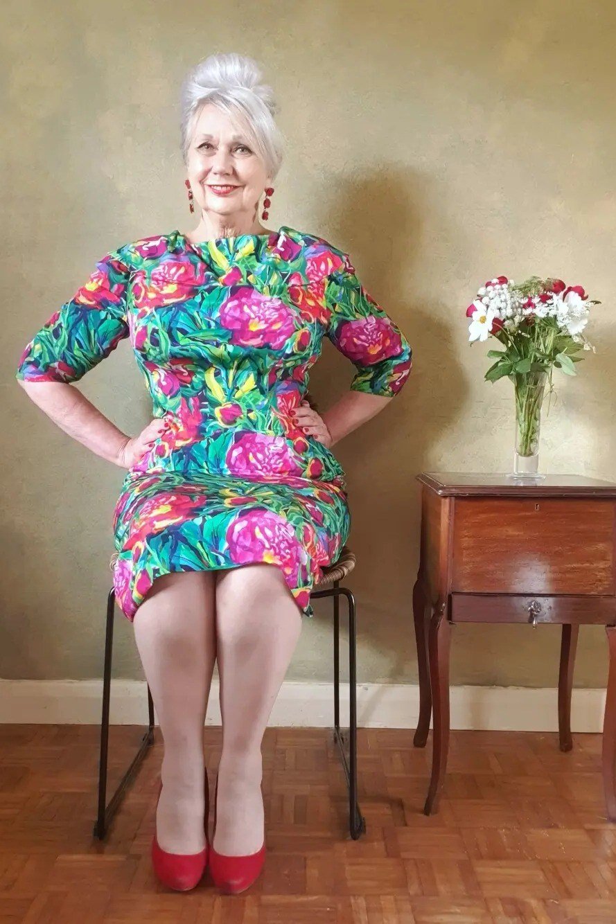 Green and pink floral dress with red heels, seated woman