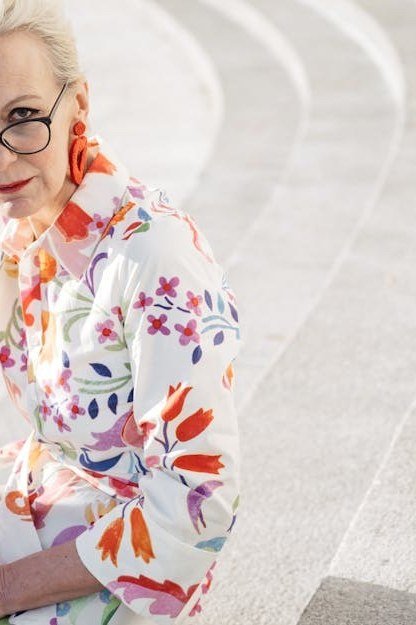 White dress with orange floral, seated woman with glasses