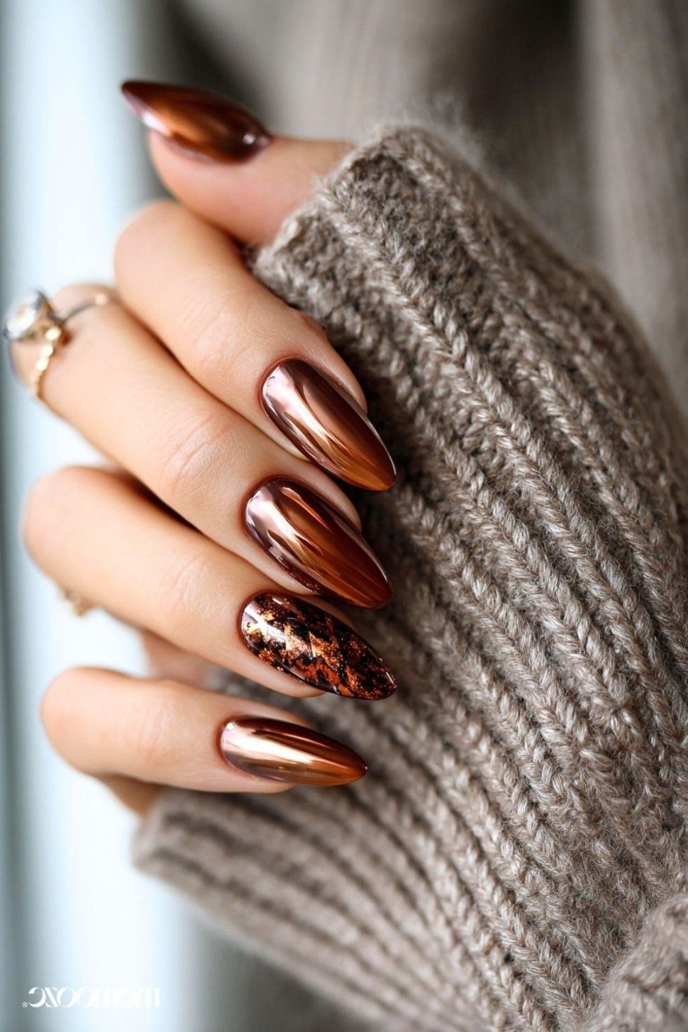 Copper chrome almond nails with leopard print accent nail, grey sweater