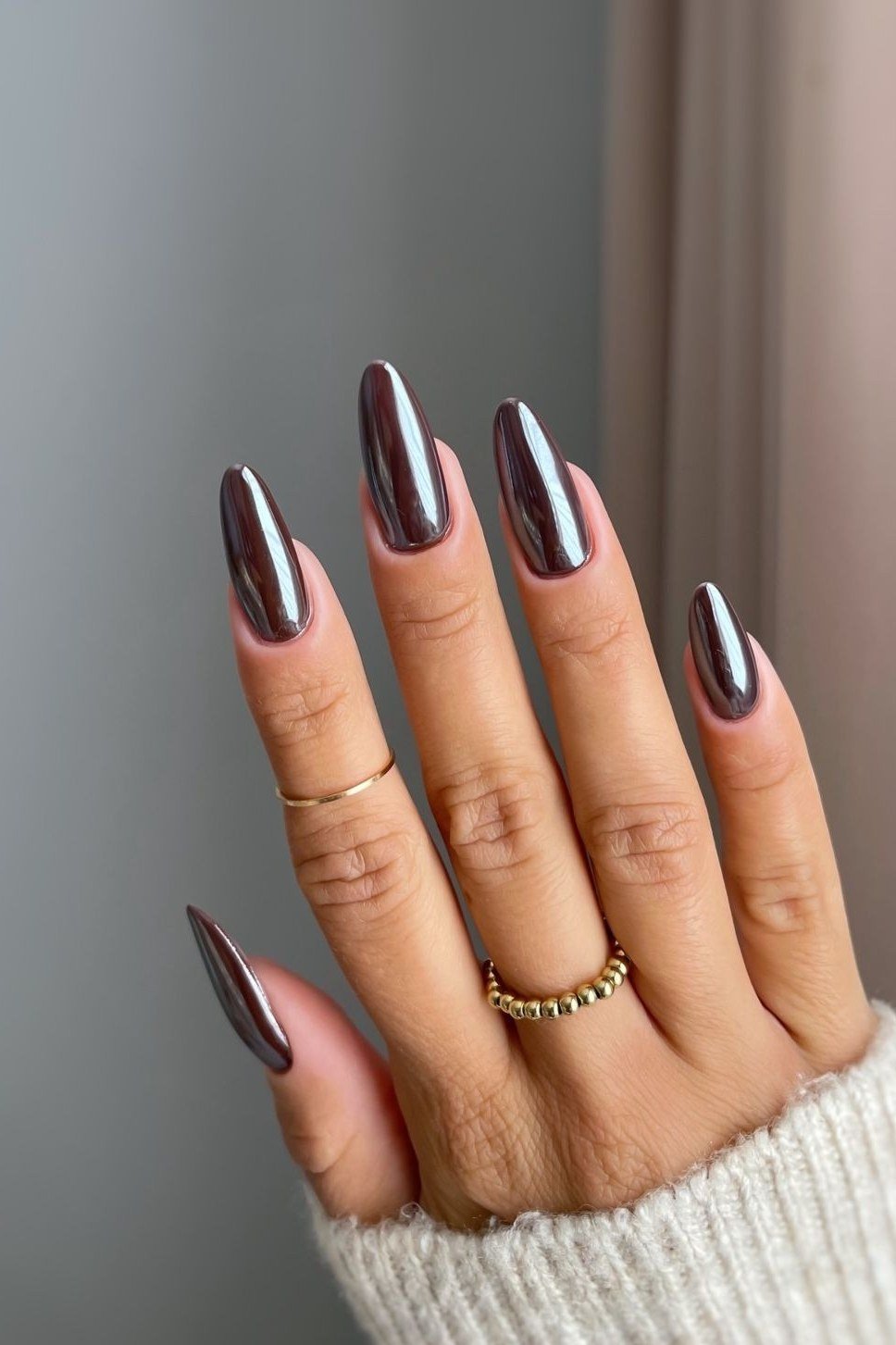 Midnight plum chrome almond nails, hand in white sweater