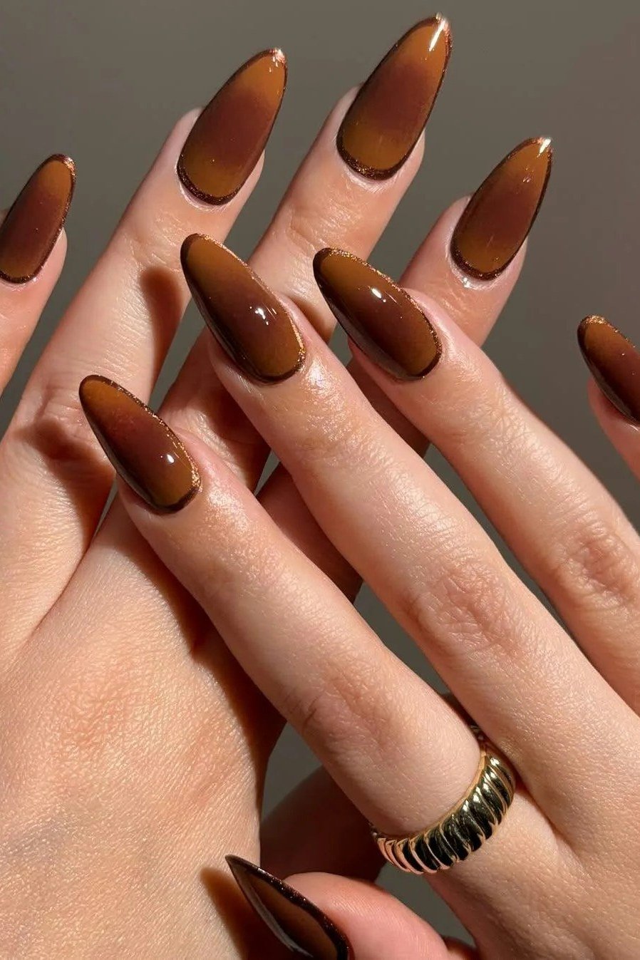 Polished copper chrome almond nails, two hands with gold ring