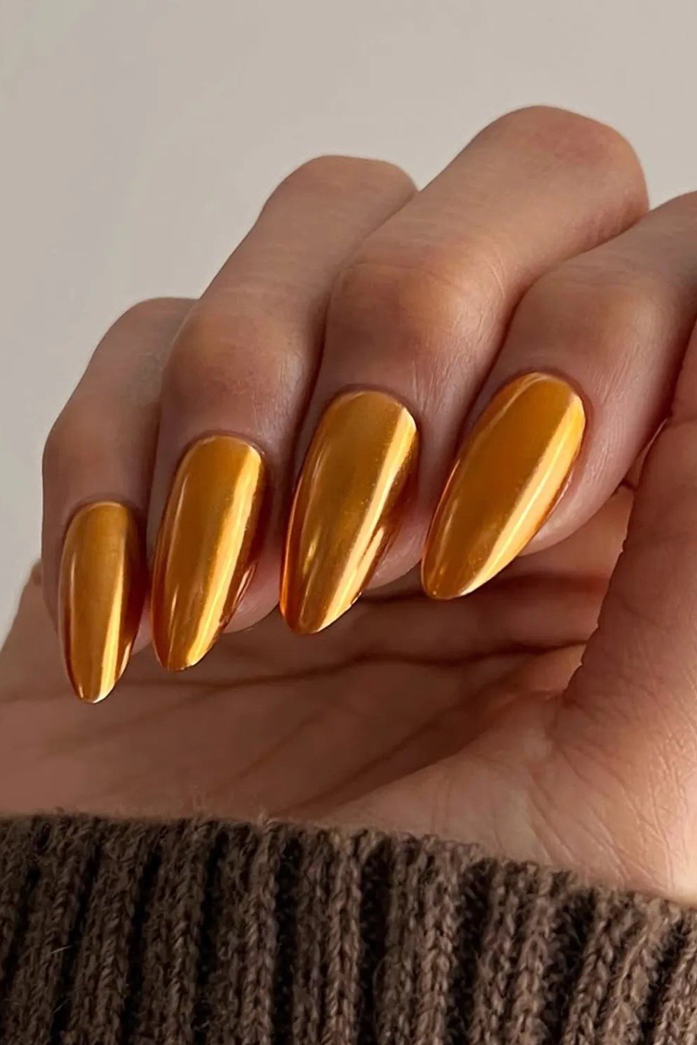 Molten gold chrome almond nails with brown sweater