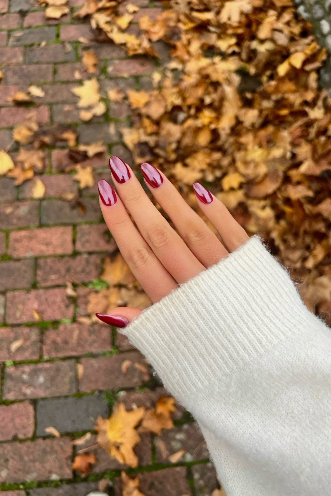 Street-style short red nails, white sweater, autumn leaves