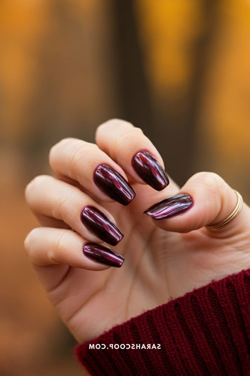 Blurred-background dark plum chrome almond nails