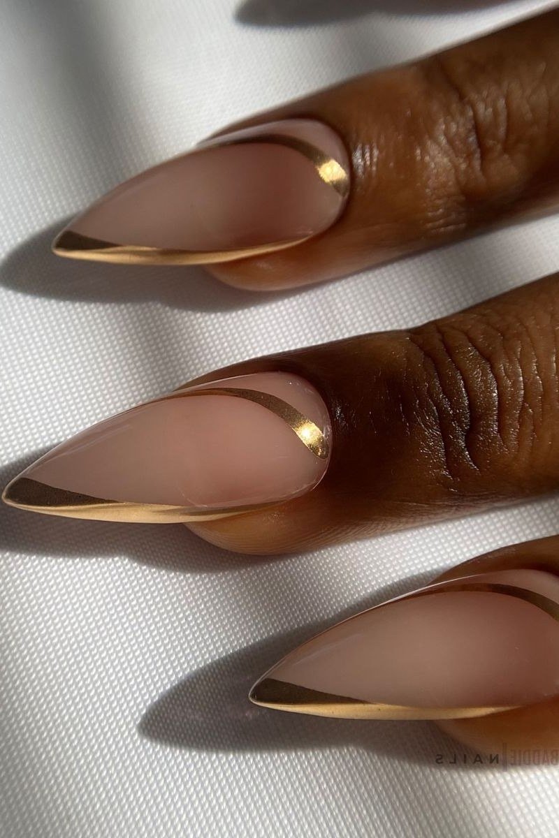 Golden French chrome tips on nude almond nails, dark skin