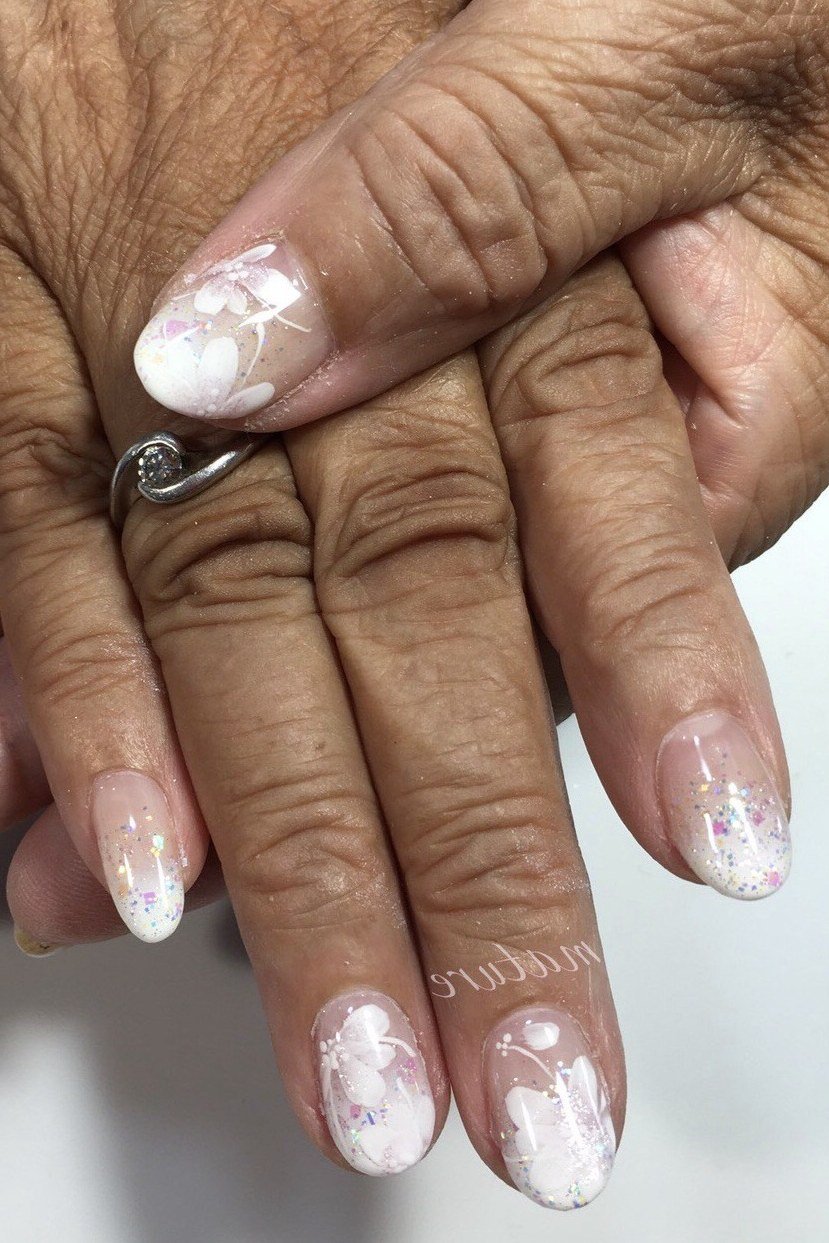 Frosted white floral nail art on nude oval nails for women over 50