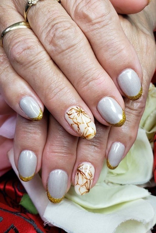 White and gold floral nail art with gold French tips for women over 50