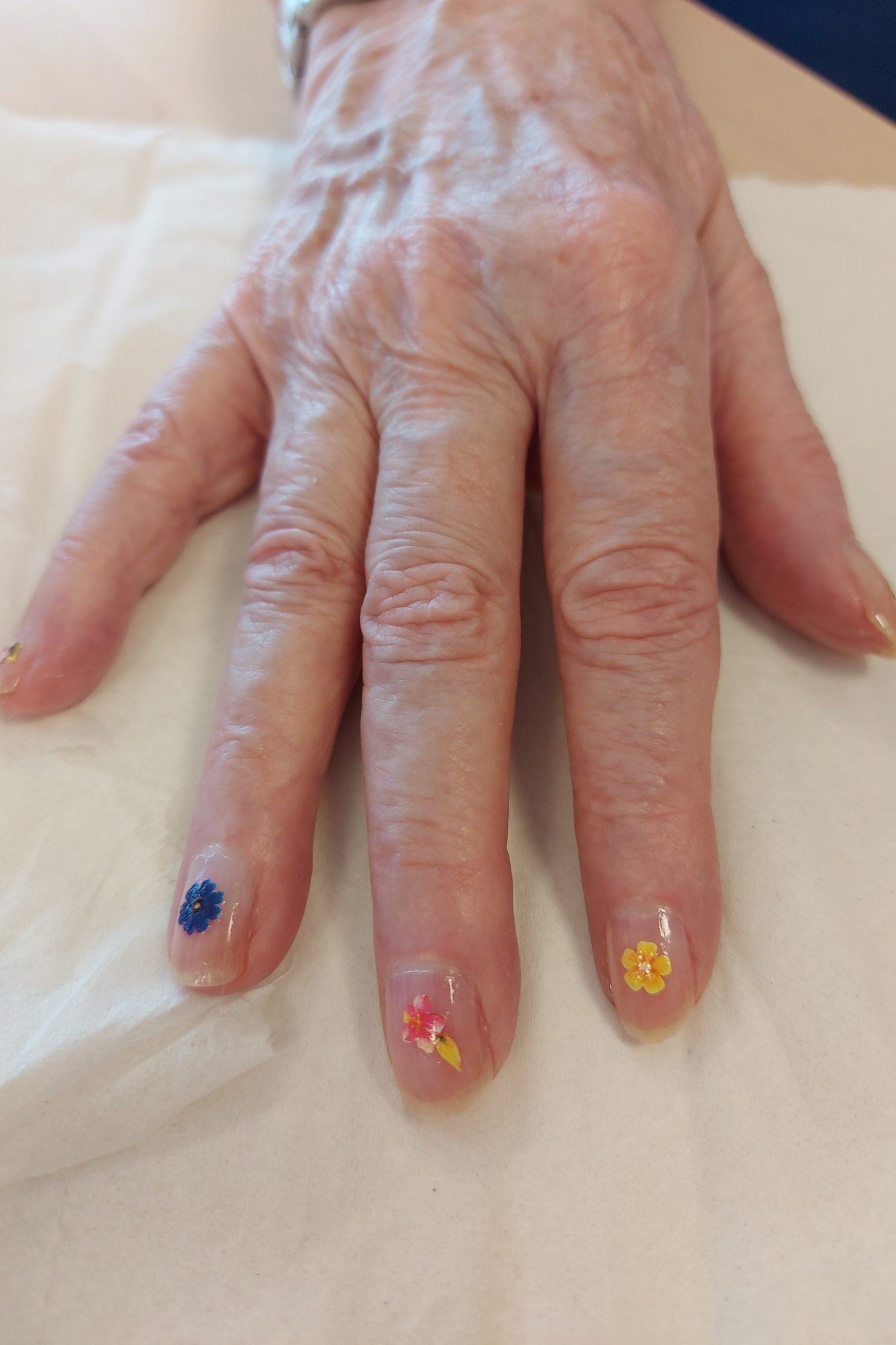 Tiny colorful flower nail art on mature hands for women over 50