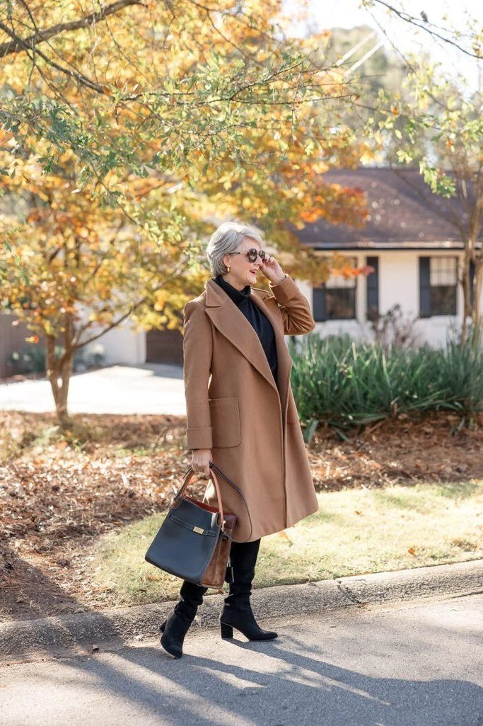 Camel wool coat, black top, dark pants, mature woman walking on street