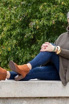 Olive turtleneck sweater, dark jeans, tan boots, older woman on park bench
